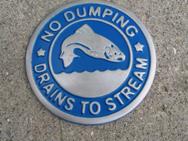 Picture of storm drain marker that says "No Dumping Drains to Stream".