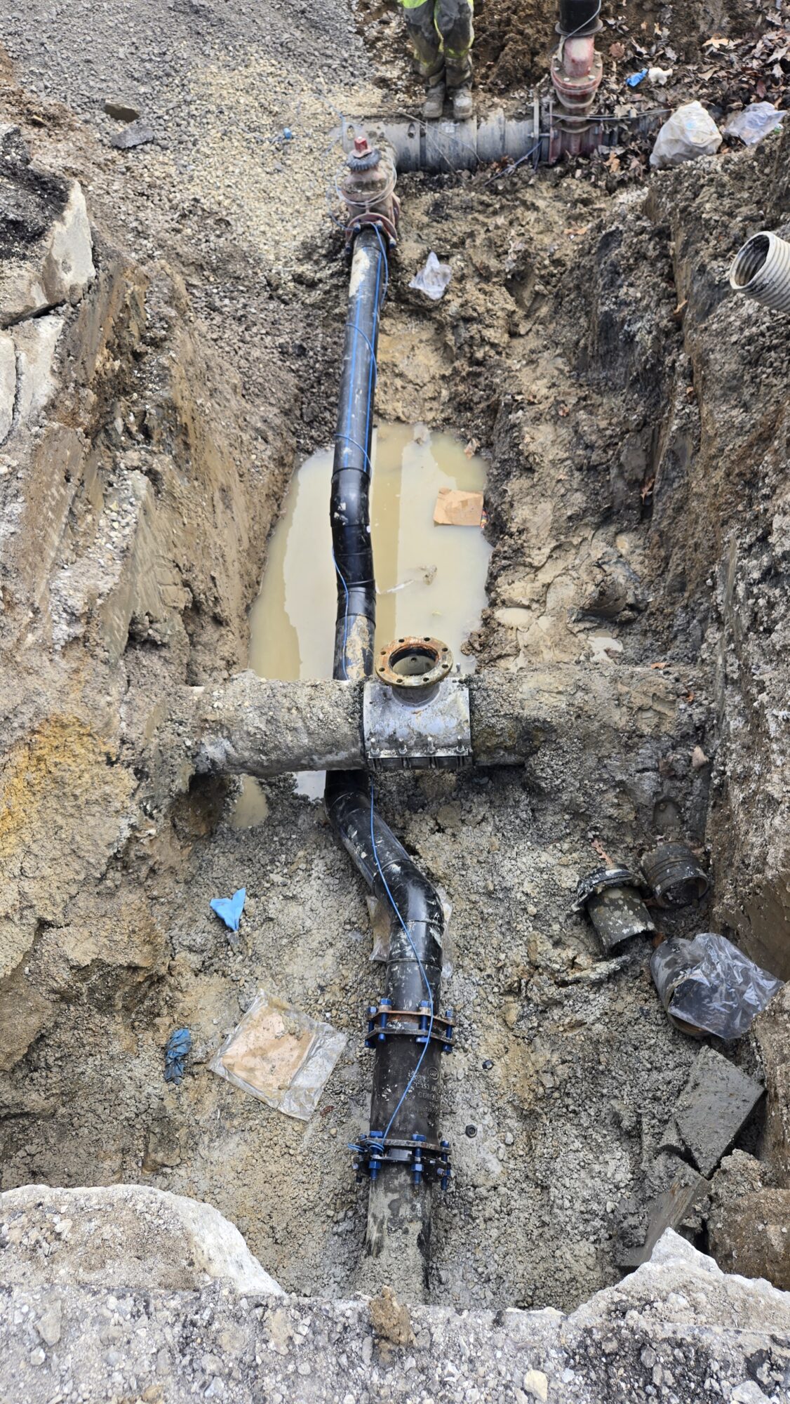 Underground view of new water main pipe connection in rubble.