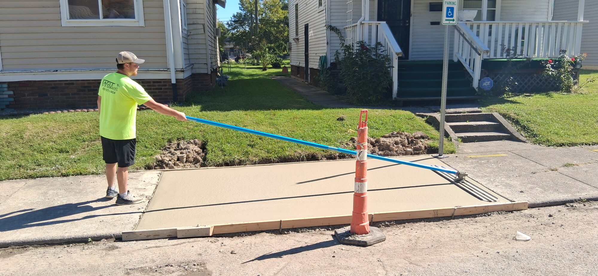 Man in yellow shirt standing on sidewalk doing concrete restoration.