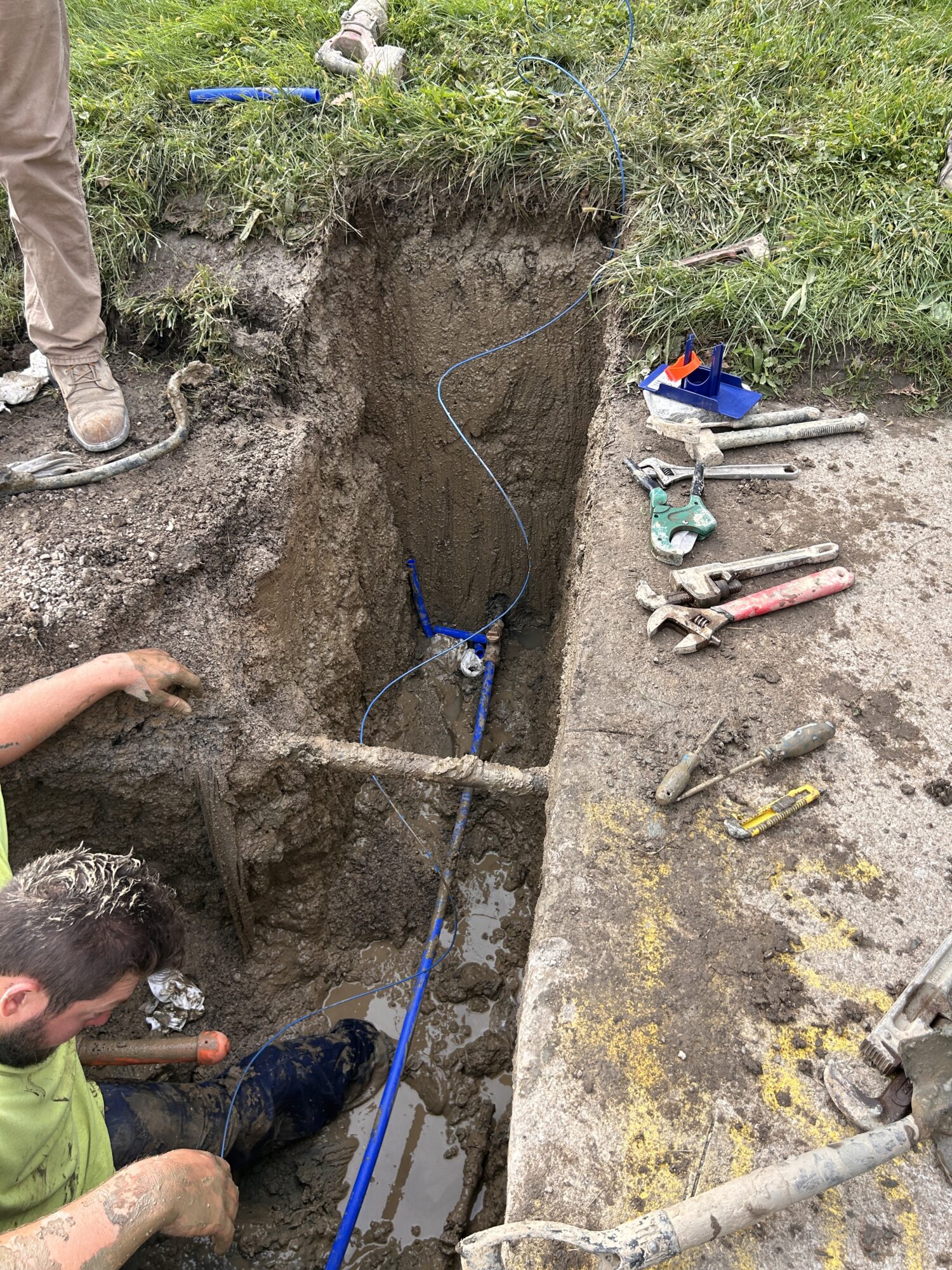 A water service line in the ground with tools and construction crew