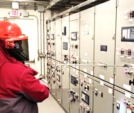 Worker attending to a bank of electrical equipment.