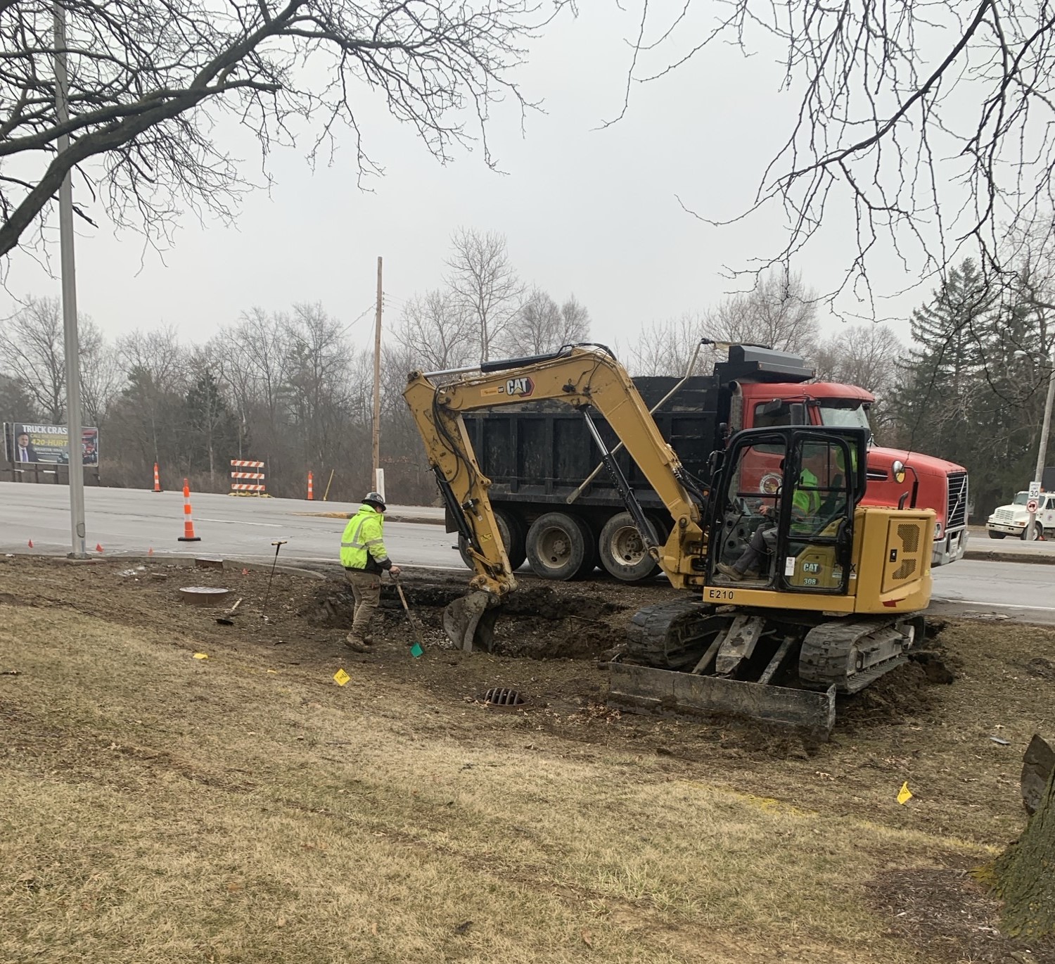 Construction crews on the side of the road digging up a hole.