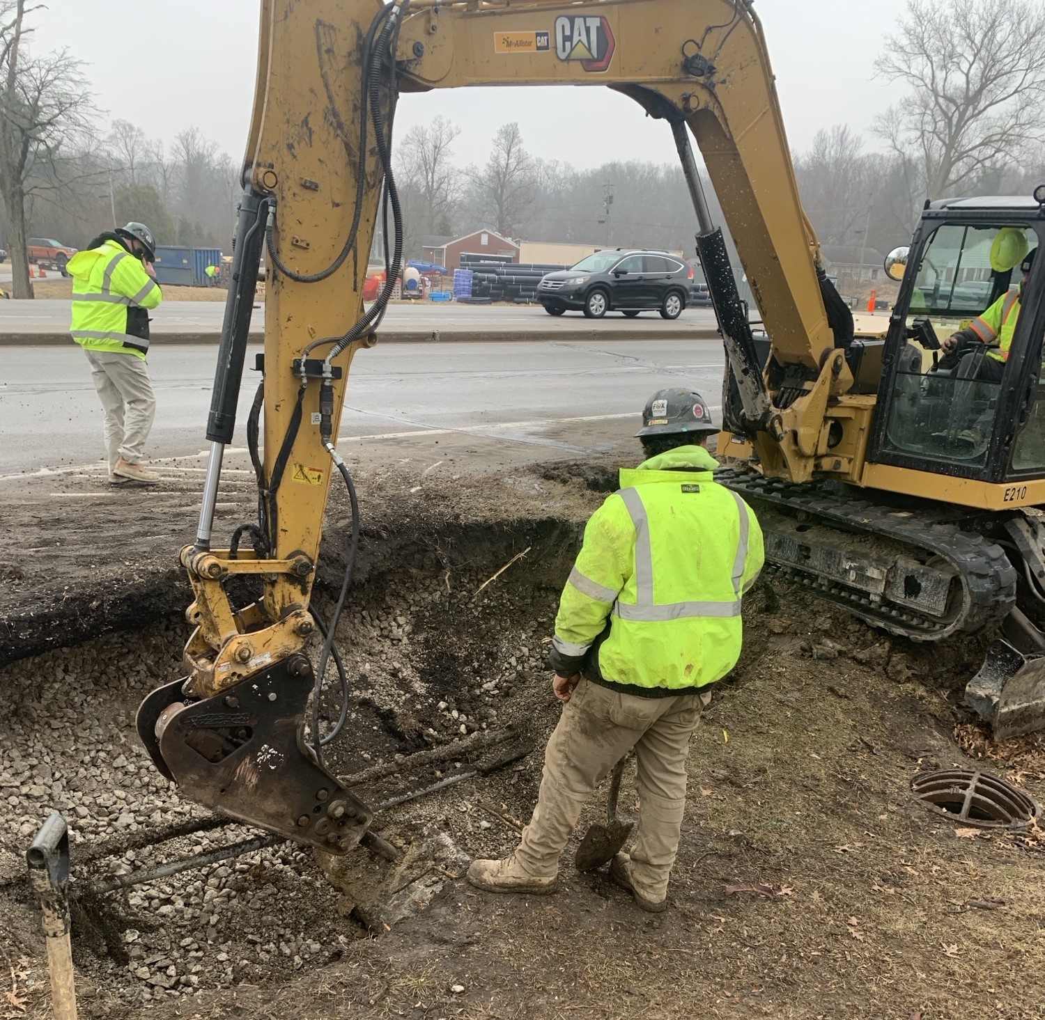 Two construction crew members watching machine jackhammer concrete underground.