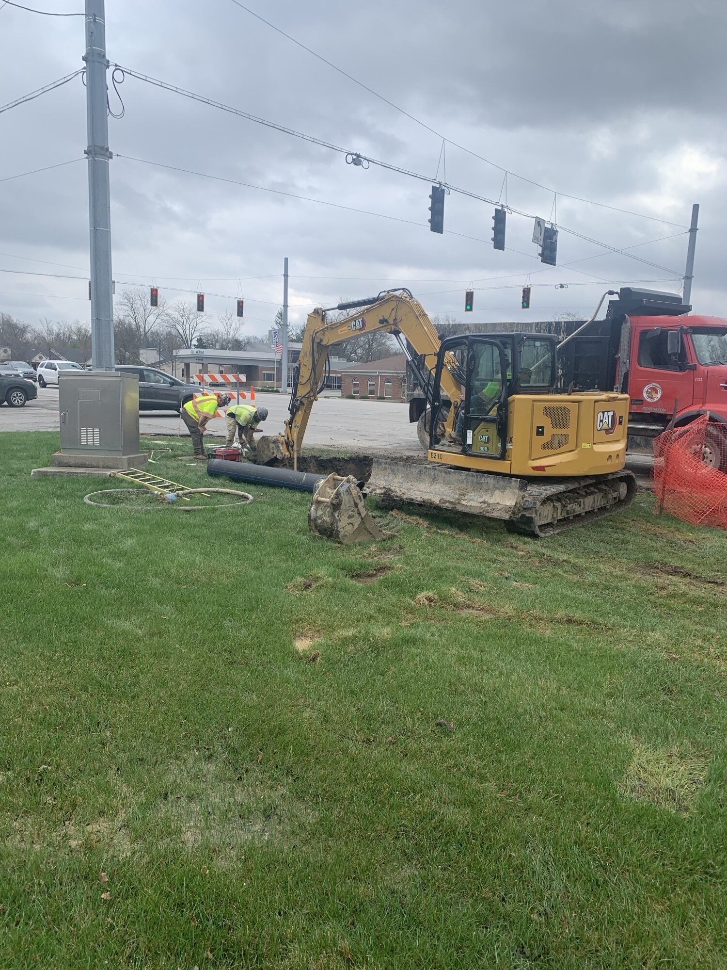 Bulldozer on the side of the road digging in the grass for water main pipe.