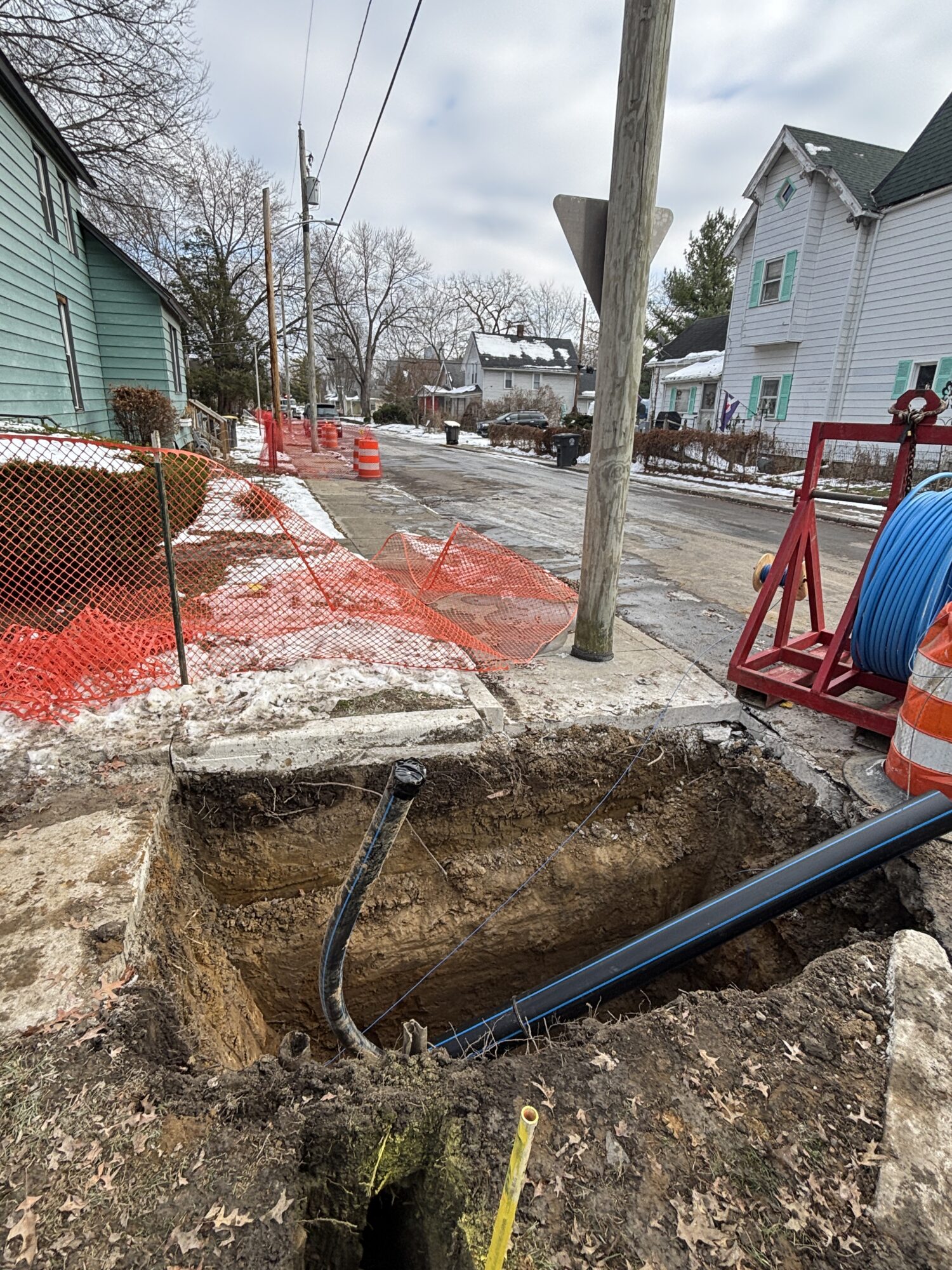 A street view of construction and a dug-out with water main pipe.